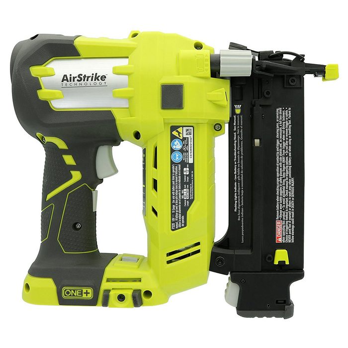 A bright yellow and gray electric nail gun sits side-on, featuring a trigger and magazine, designed for fastening materials in construction or woodworking.