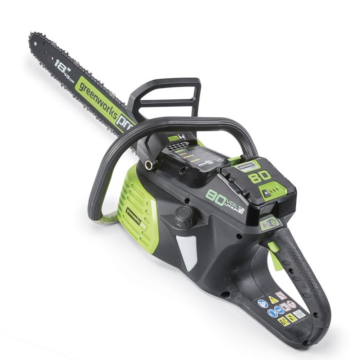 A chainsaw is positioned diagonally, with its blade visible. It shows a green and black design, featuring labels and battery indicators, suggesting usage for cutting wood.