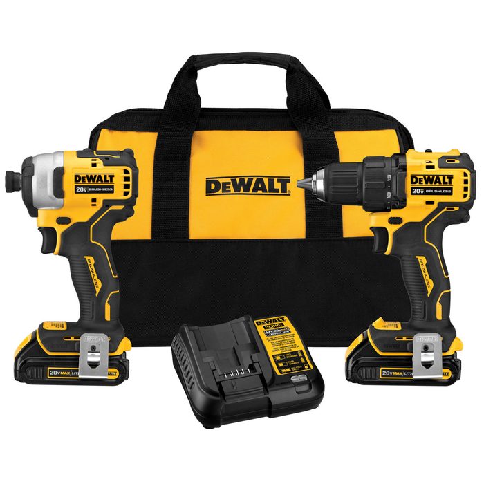 Two cordless power tools, a drill and an impact driver, are placed next to a battery charger, all packaged in a black and yellow DEWALT bag.