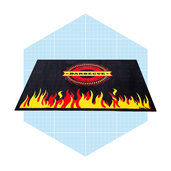 A barbecue-themed mat displays flames and a circular logo. It lies flat against a light blue, grid-patterned background, emphasizing its vibrant design.