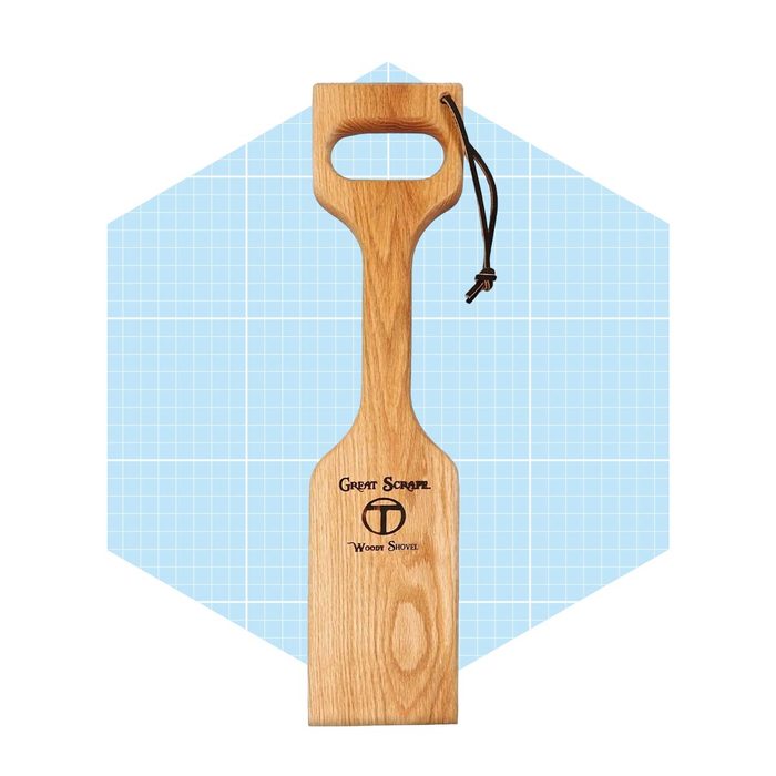 A wooden spatula with a handle rests against a light blue grid background, featuring the text 