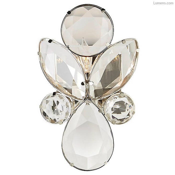 A crystal brooch sparkles, with multiple faceted shapes arranged in a floral pattern, reflecting light in a bright, neutral environment.