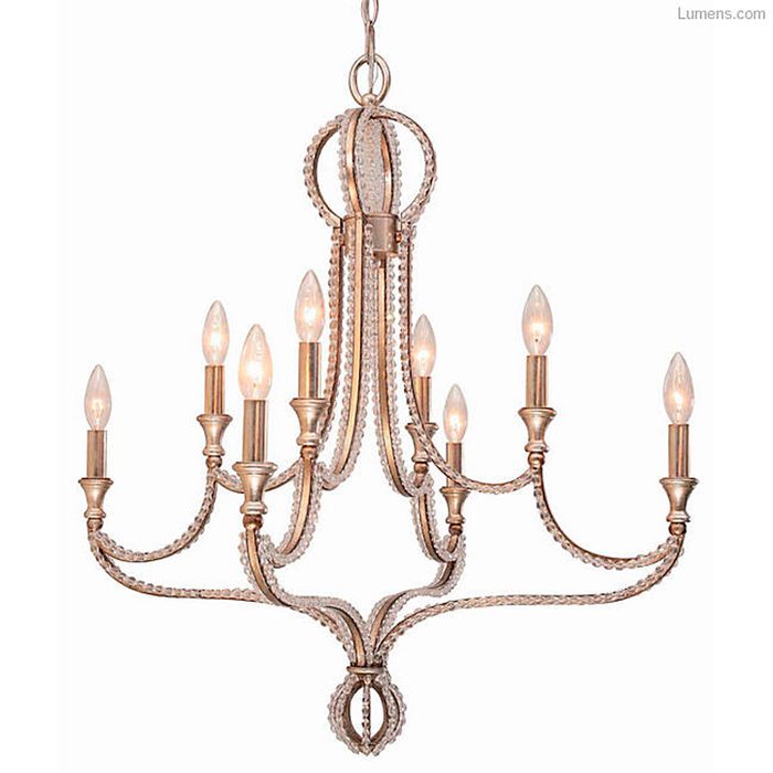 A decorative chandelier with multiple light bulbs hangs from the ceiling, emitting a warm glow in an elegant setting.