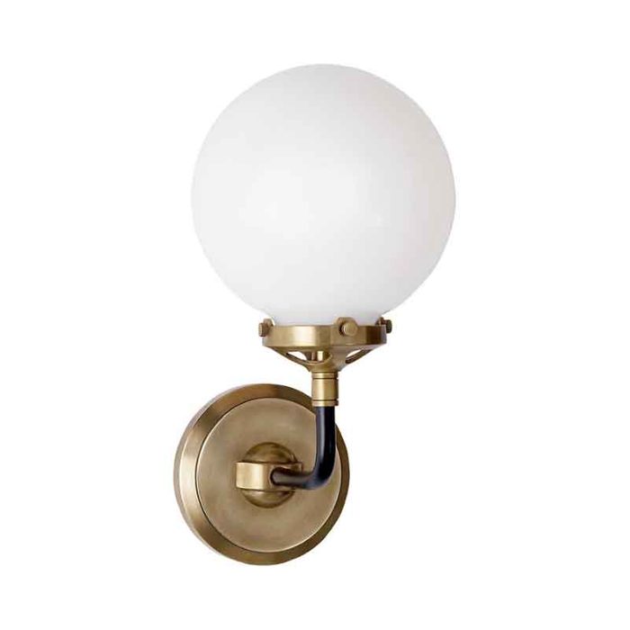 A round, opaque light globe is mounted on a circular brass backplate, creating a stylish wall sconce for illuminating indoor spaces.