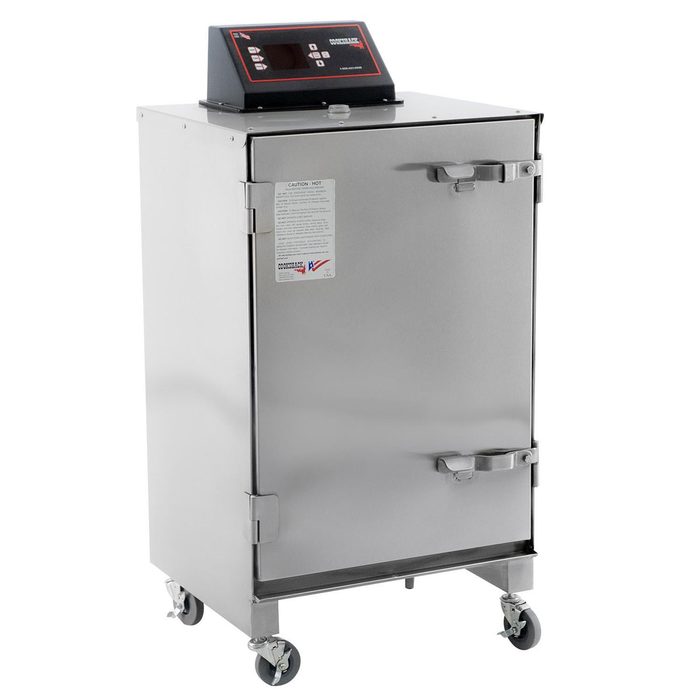 A stainless steel smoker cabinet stands on wheels, featuring a digital control panel on top and a securely closed front door, used for cooking food.