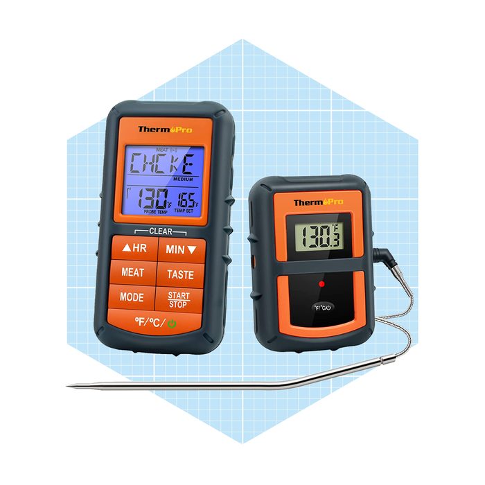 A digital meat thermometer displays temperatures and settings, measuring food doneness while placed against a backdrop of light blue grid patterns.