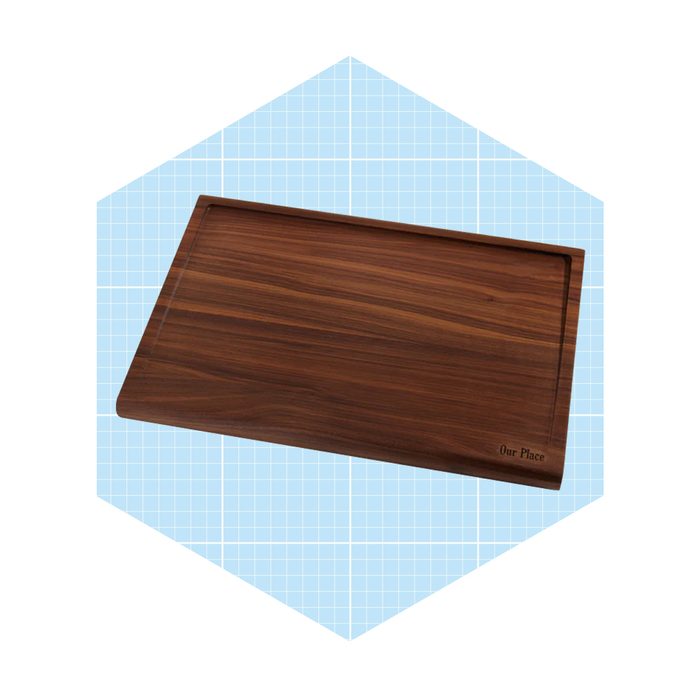 A wooden serving tray rests flat, featuring a raised edge on one side, set against a light blue grid background.