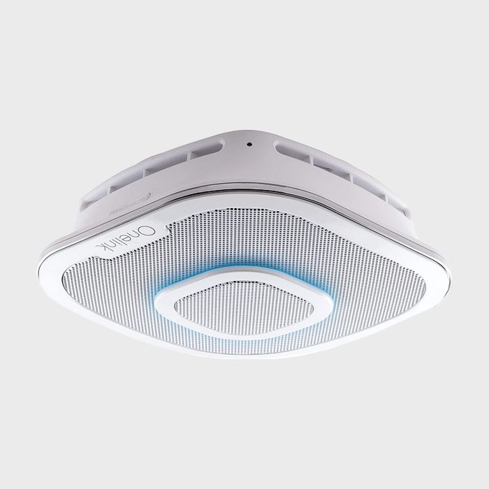 A white, ceiling-mounted air purifier operates quietly, featuring a prominent blue light and a mesh surface for air filtration in a neutral environment.