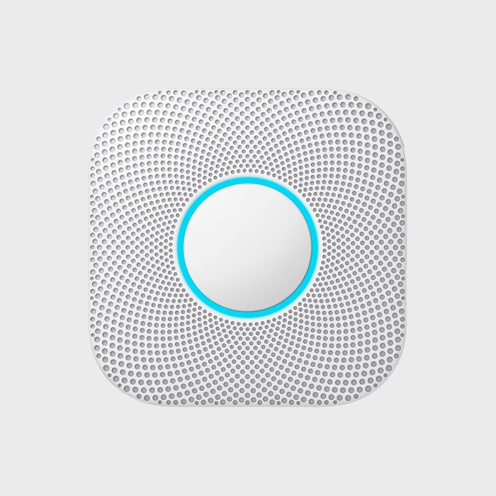 A round, textured white device with a blue circular detail at its center rests on a plain gray background.