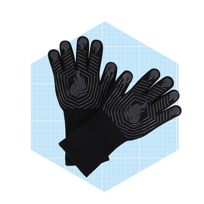 Black heat-resistant gloves rest on a light blue grid background, showcasing textured fingers designed for grip and a flame pattern for safety in cooking or grilling.