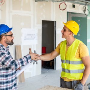 Engineer and architect handshake at meeting with successful construction project.Architect and building engineer have handshake on construction site. Building workers shaking hand inside industrial objec