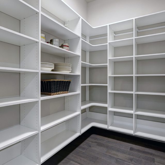 Empty pantry interior with white shelves and dark floor